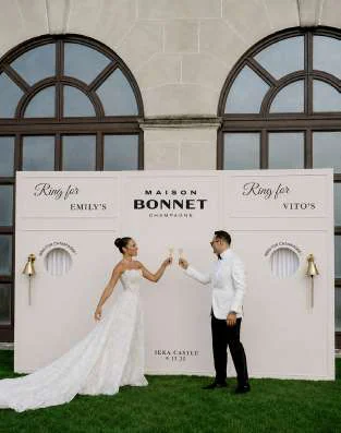 Noivos a brindar em frente à parede Ring for Champagne personalizada